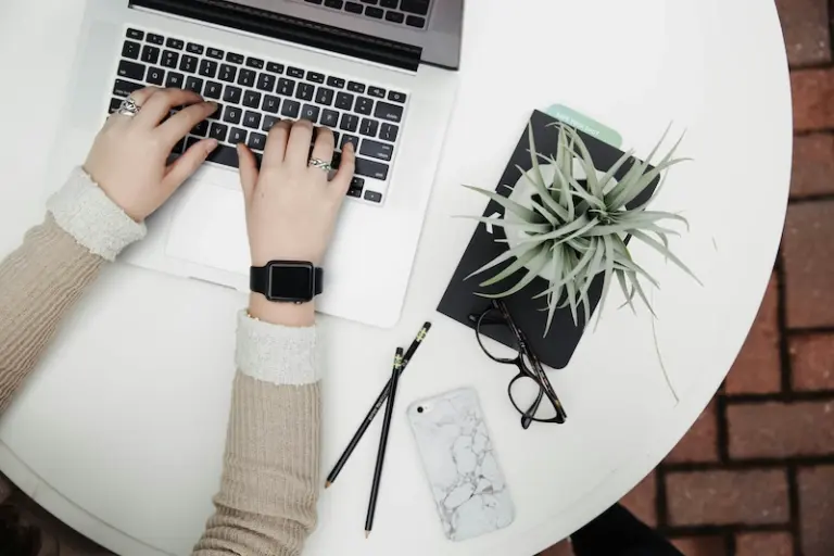 Woman working on laptop with smartwatch and smartphone