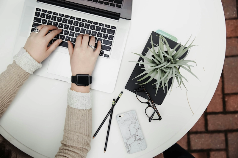 Woman working on laptop with smartwatch and smartphone