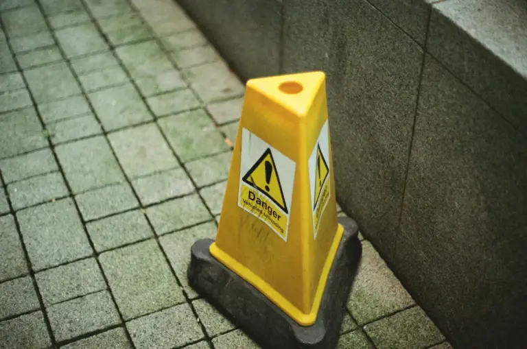 Yellow hazard sign on cobblestone path