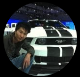 Man posing with white Ford Mustang at car show