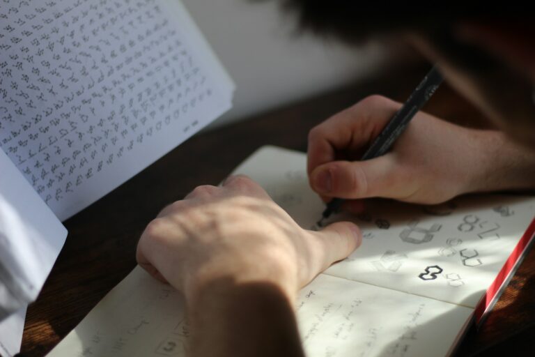 Person writing detailed notes with pen in notebook