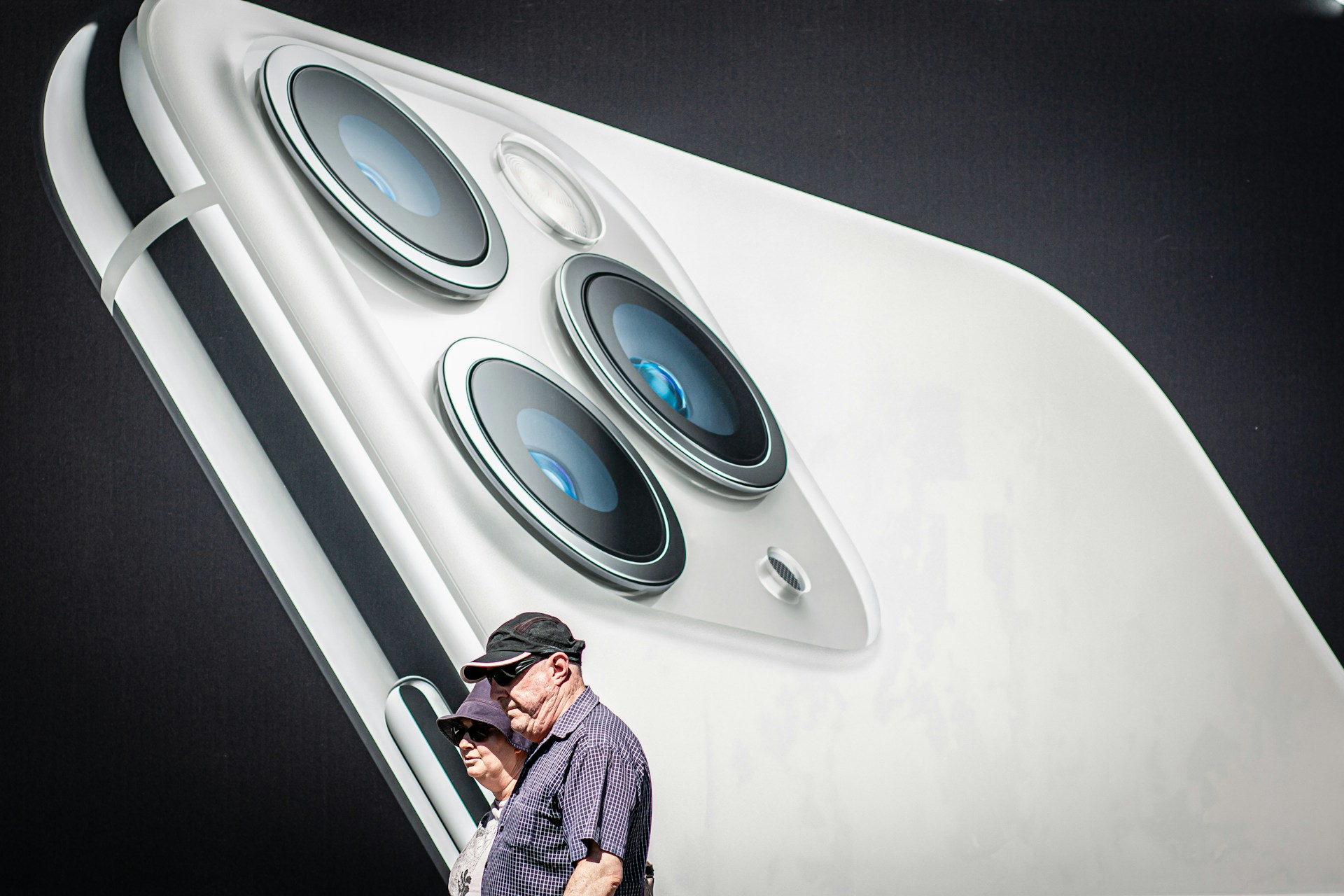 Elderly couple walking by giant smartphone camera display