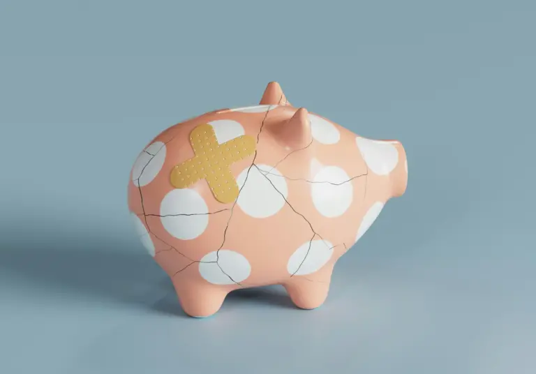 Cracked piggy bank with adhesive bandage on blue background