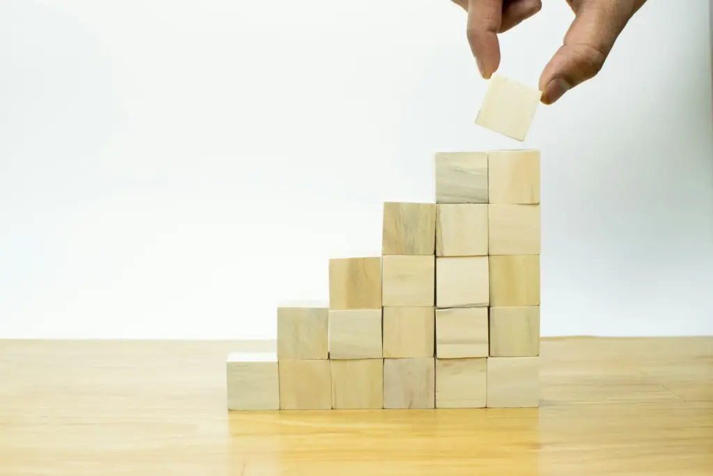 Hand placing wooden block on growing stack