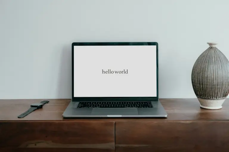 Laptop on desk displaying 'hello world' text