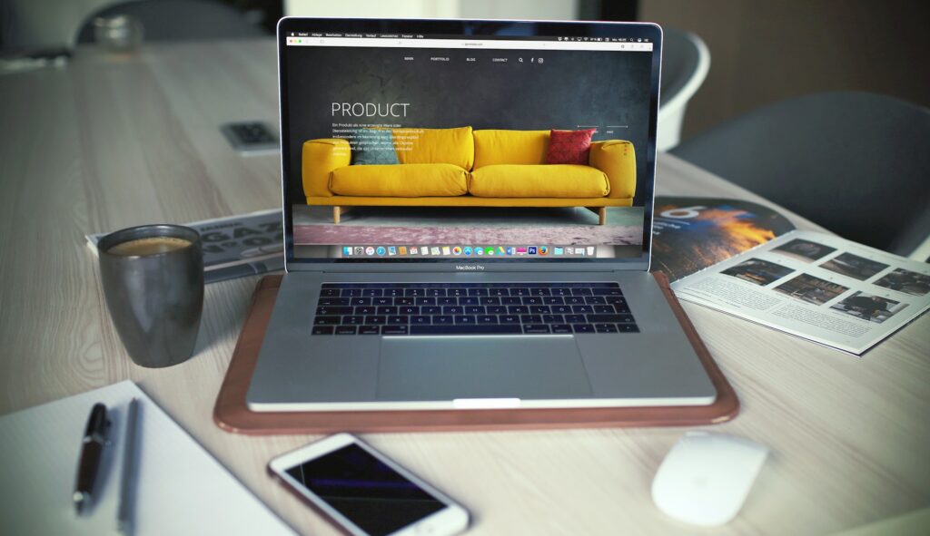 Laptop displaying furniture website on desk with accessories