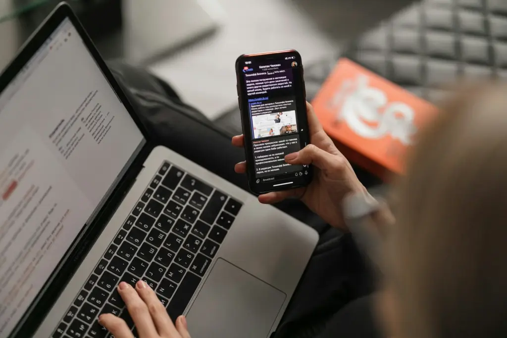 Person using smartphone and laptop simultaneously