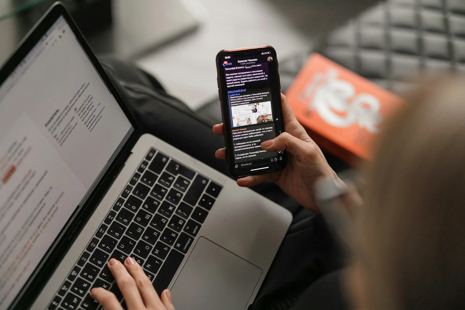 Person using smartphone and laptop simultaneously